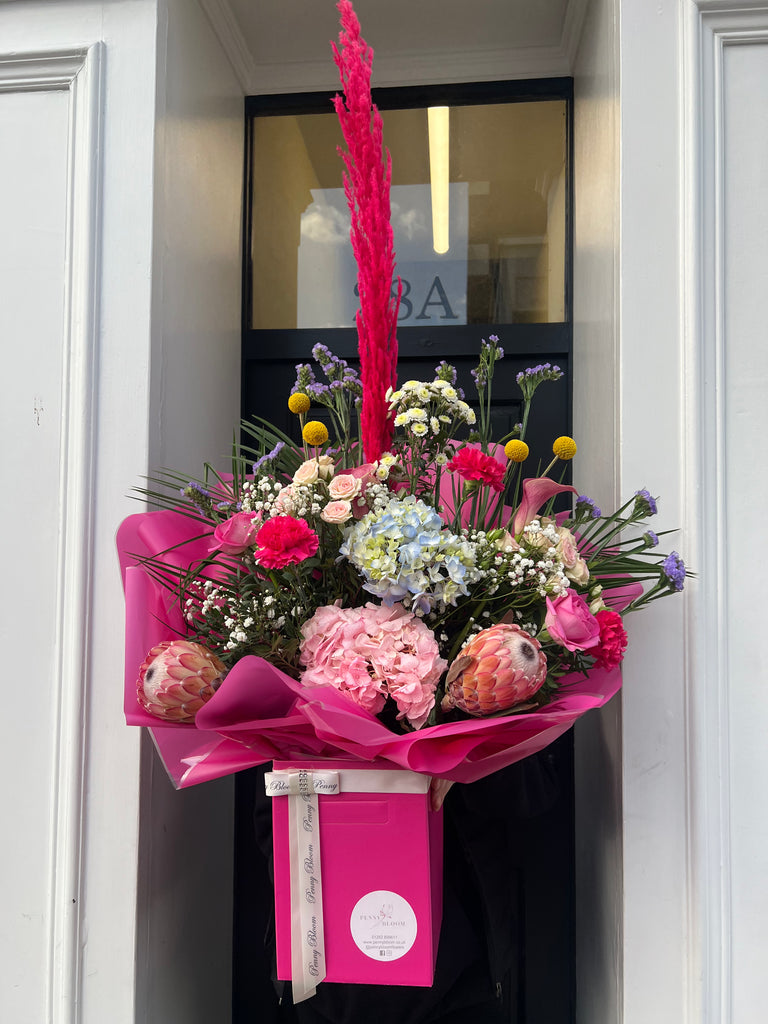 bright pink bouquet with pampas grass, hydrangeas, protea, cryspedia, roses, carnations and palm leaves.