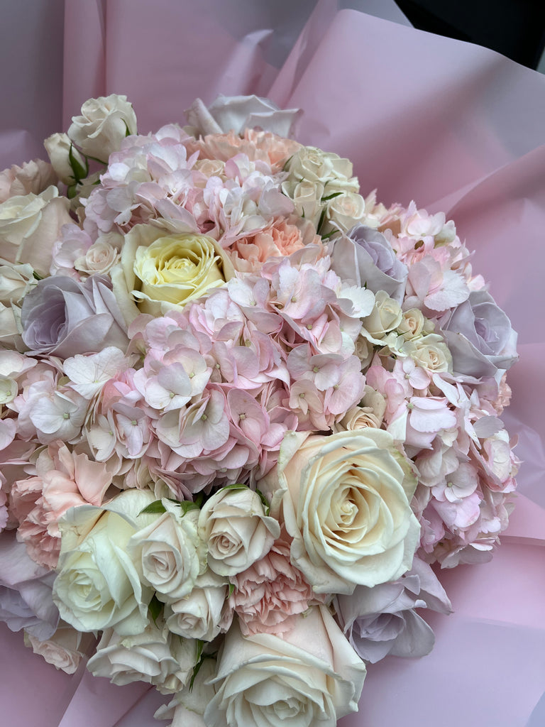 cloud of penny bloom pink hydranges, avalanche roses, spray roses, carnations and lilac roses wrapped in pink wrap 