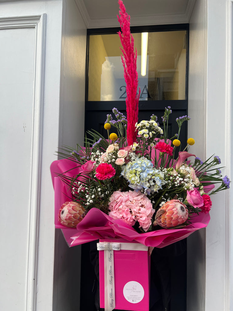 bright pink bouquet with pampas grass, hydrangeas, protea, cryspedia, roses, carnations and palm leaves.